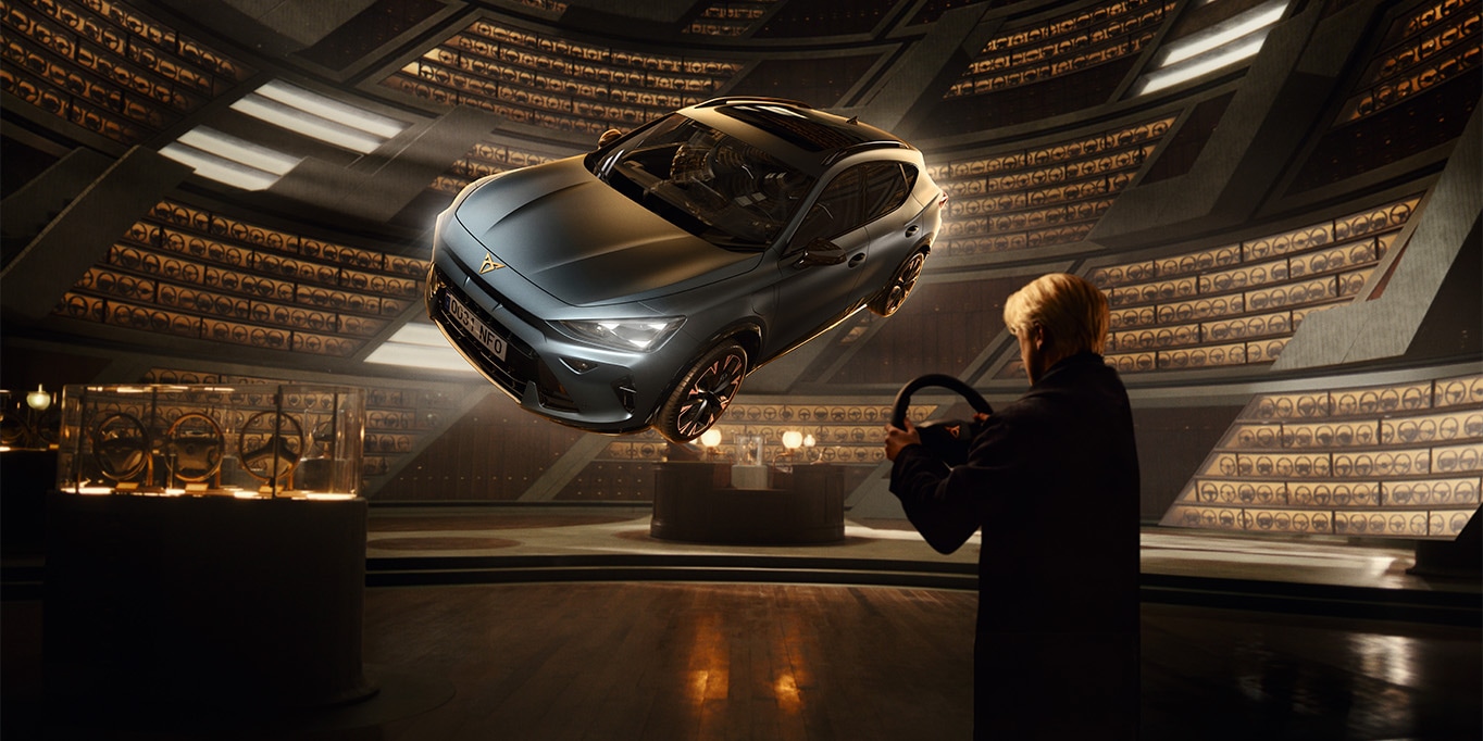 A cinematic wide shot from the CUPRA plug-in hybrid campaign; a driver stands in a vast, circular, wood-panelled archive holding a steering wheel. In the centre, a dark grey CUPRA Formentor levitates dramatically, illuminated by beams of light within the infinite, library-like structure.