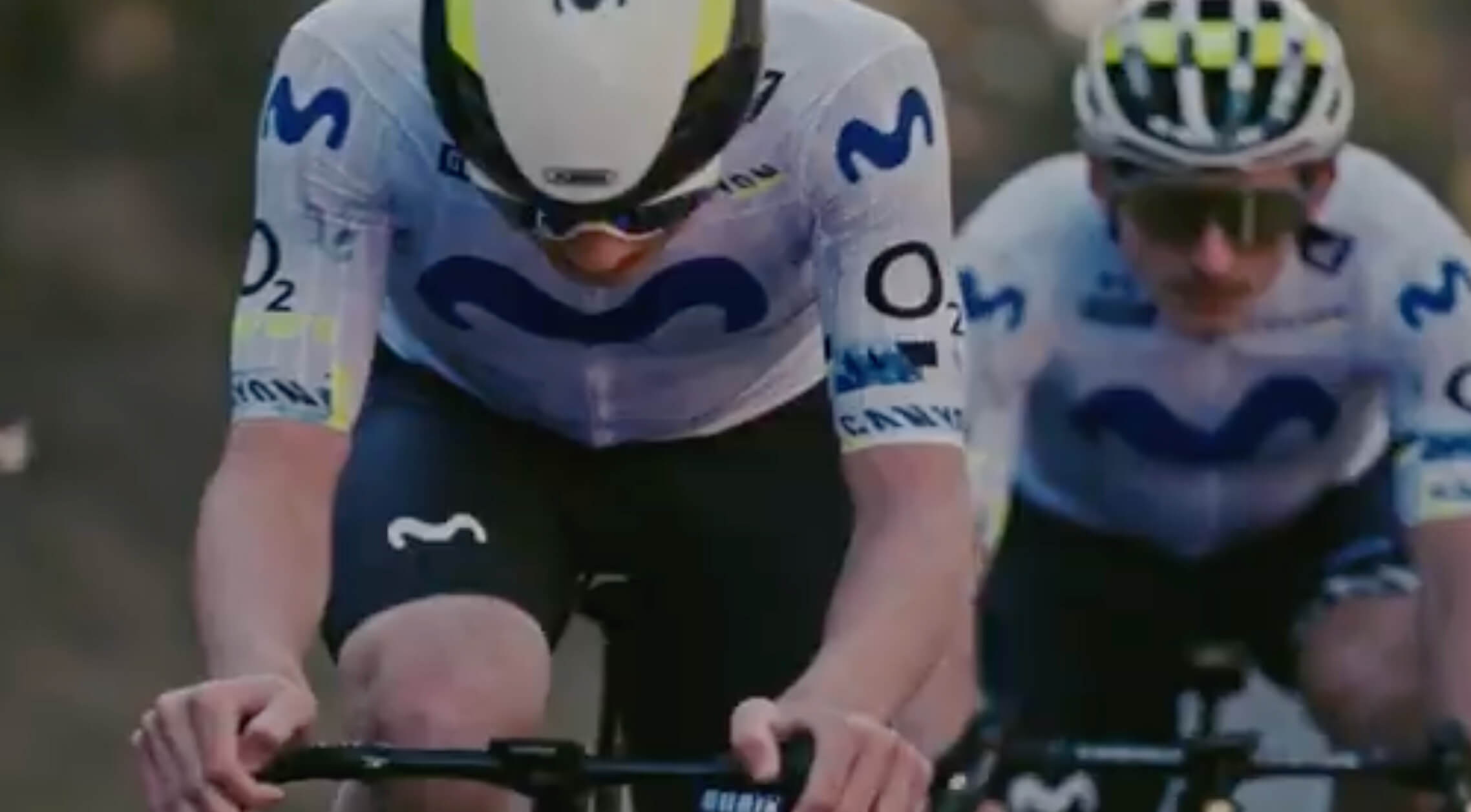 Men riding a bike with helmets and attire with the movistar logo.