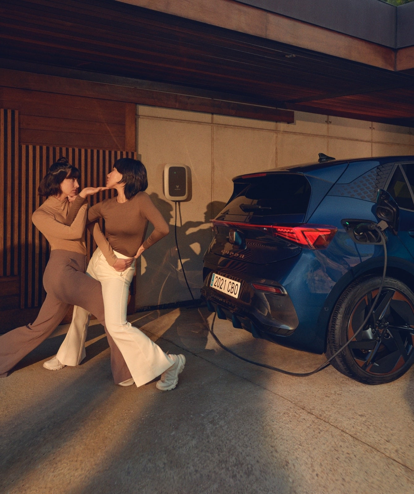 Women posing next to a  CUPRA Born charging at home