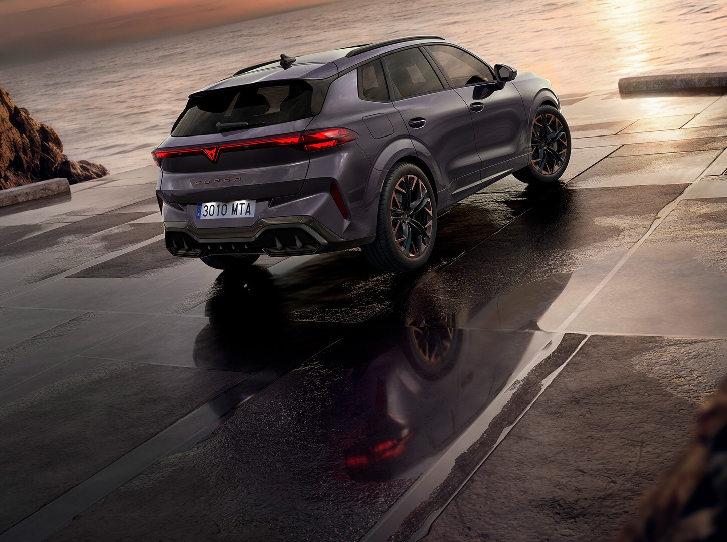 Rear-view of the CUPRA Terramar parked in a concrete surface facing the sea.