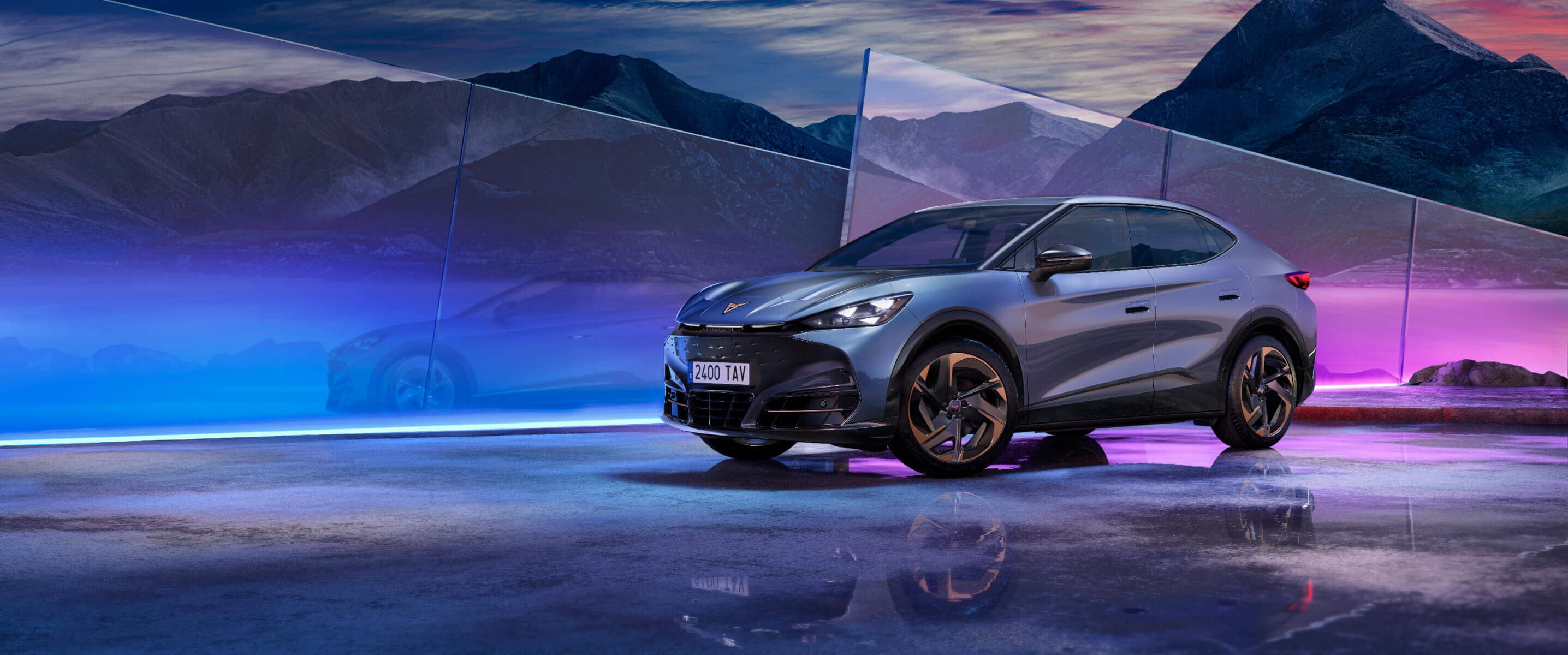 A grey CUPRA tavascan, on a front view angle, surrounded by multicolored dimmed lights.