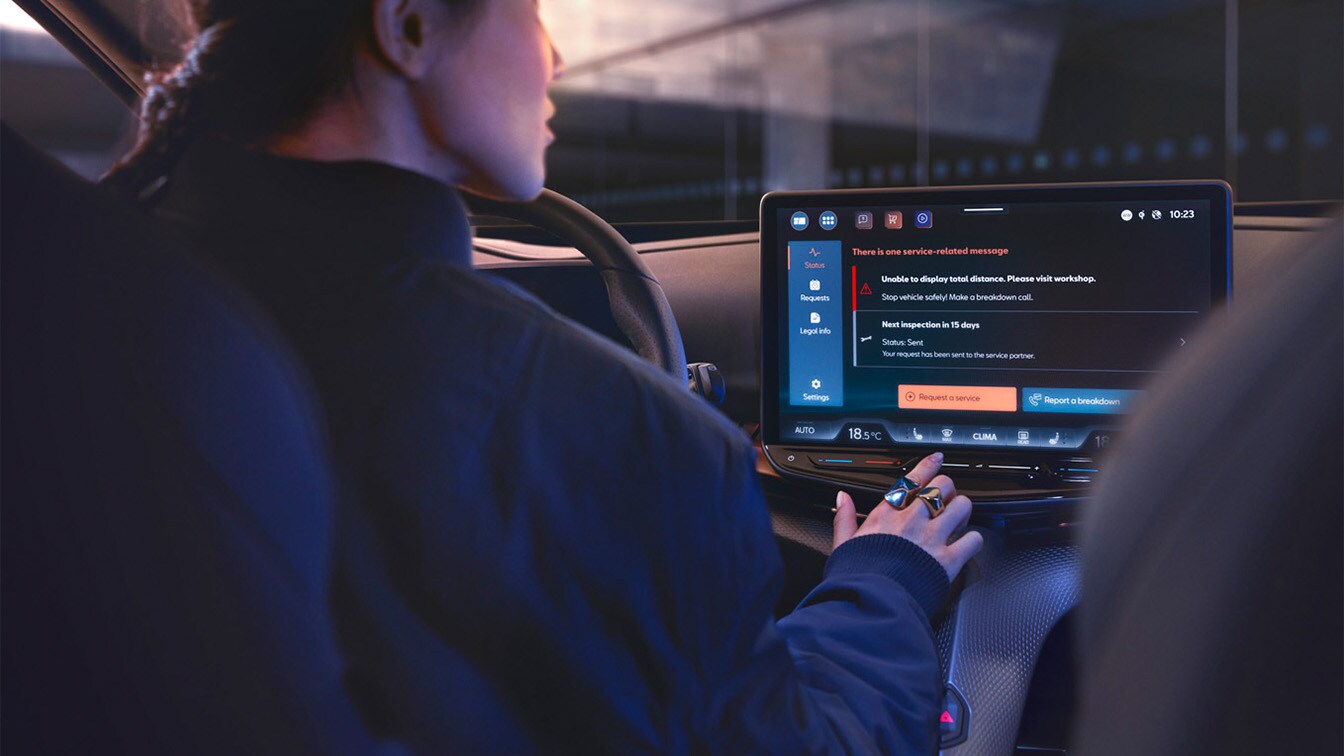 Interior view of a CUPRA car with the driver looking at the infotainment screen, which displays a service-related alert message regarding a vehicle inspection visit.