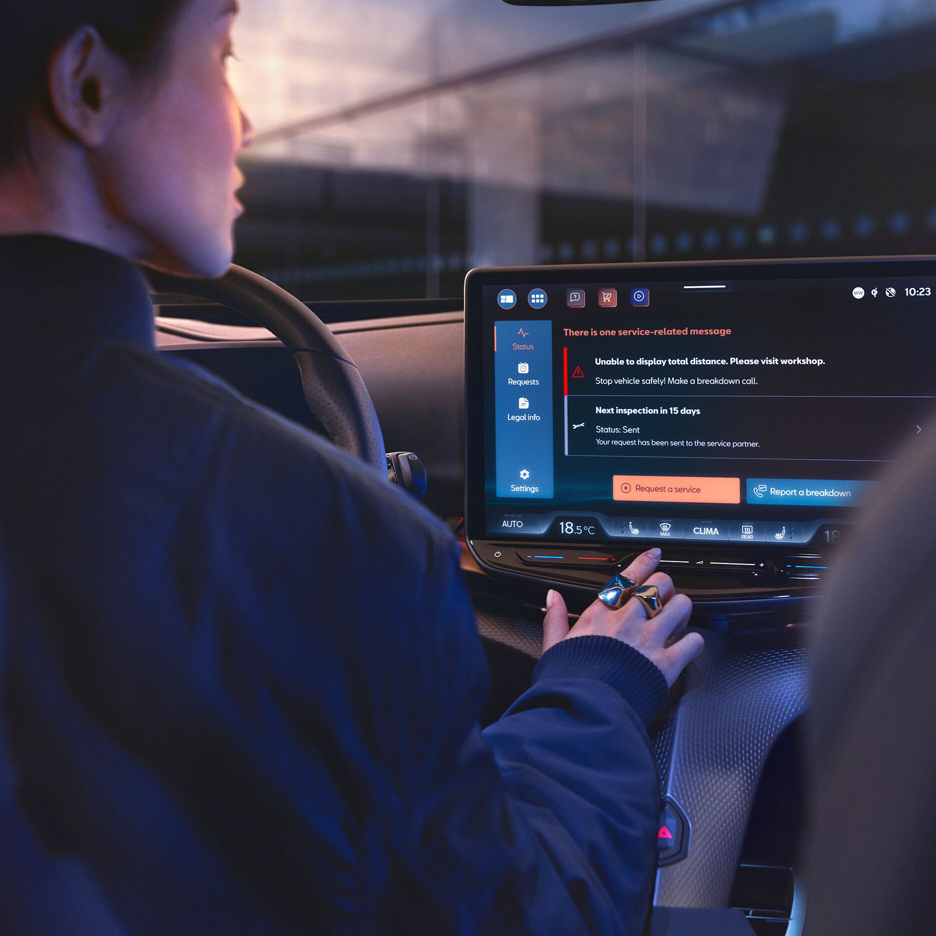 A person in the driver's seat of a CUPRA car looks at the central touchscreen infotainment system, which is displaying service and vehicle-related messages. The person's hand is visible near the controls.