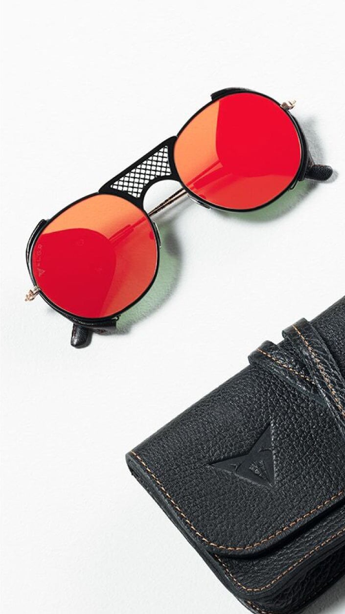 A minimalist image featuring a person wearing a dark hooded garment with subtle metallic details, against a black background.